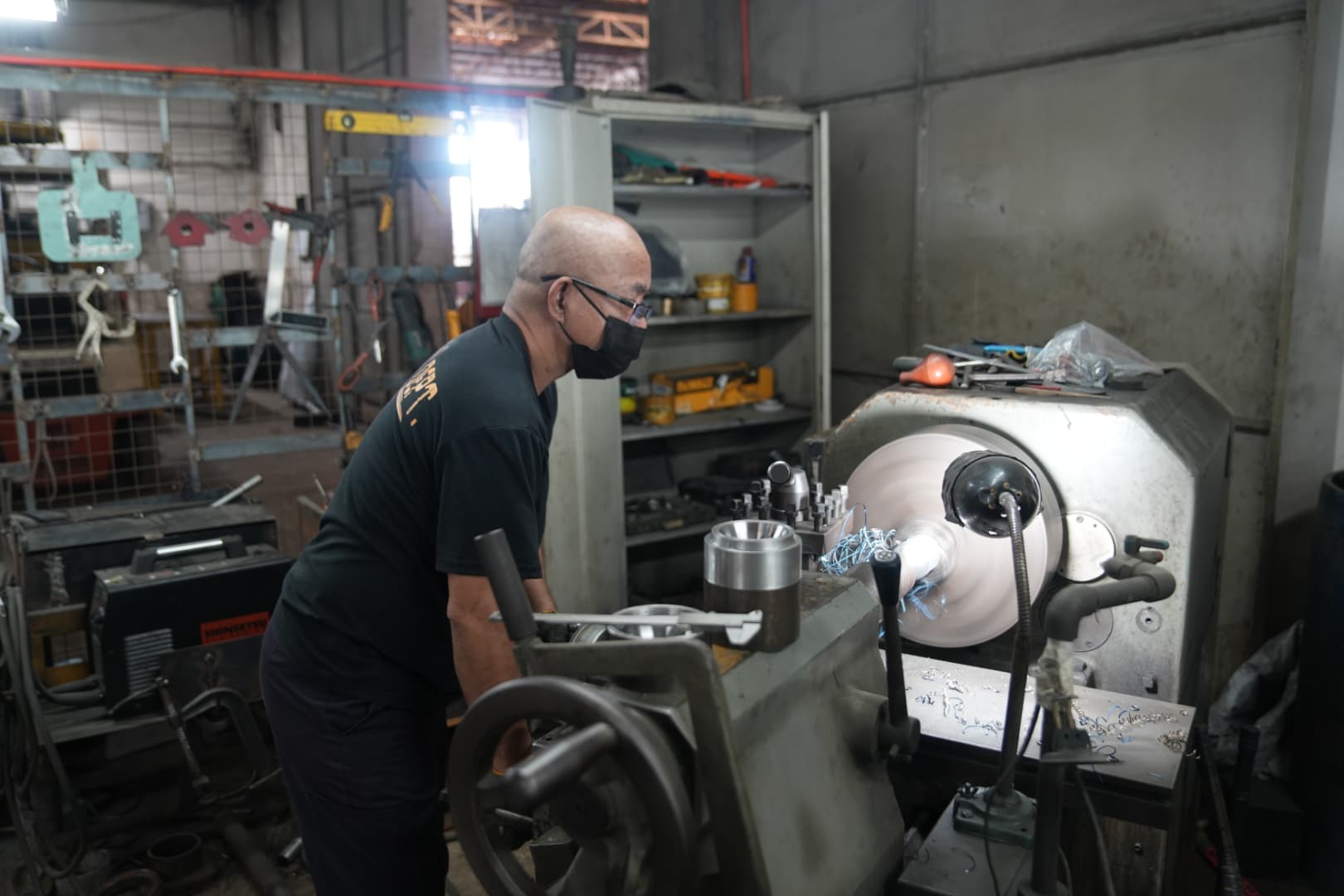 Machinist operating lathe machine shaping precision metal mold for rubber products